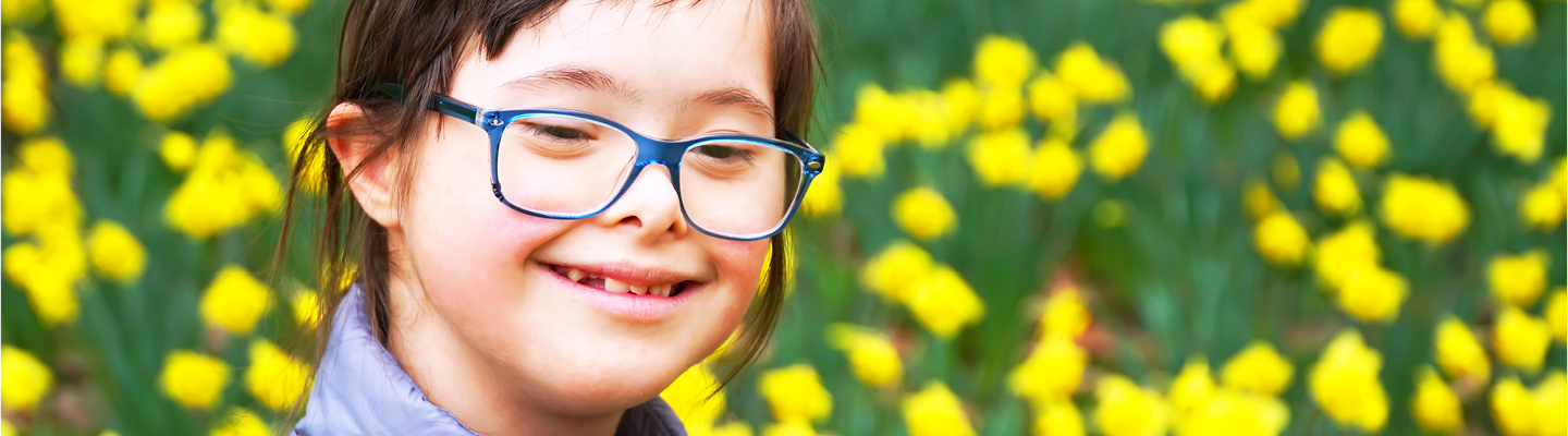 Portrait of child with Down Syndrome in flowery field