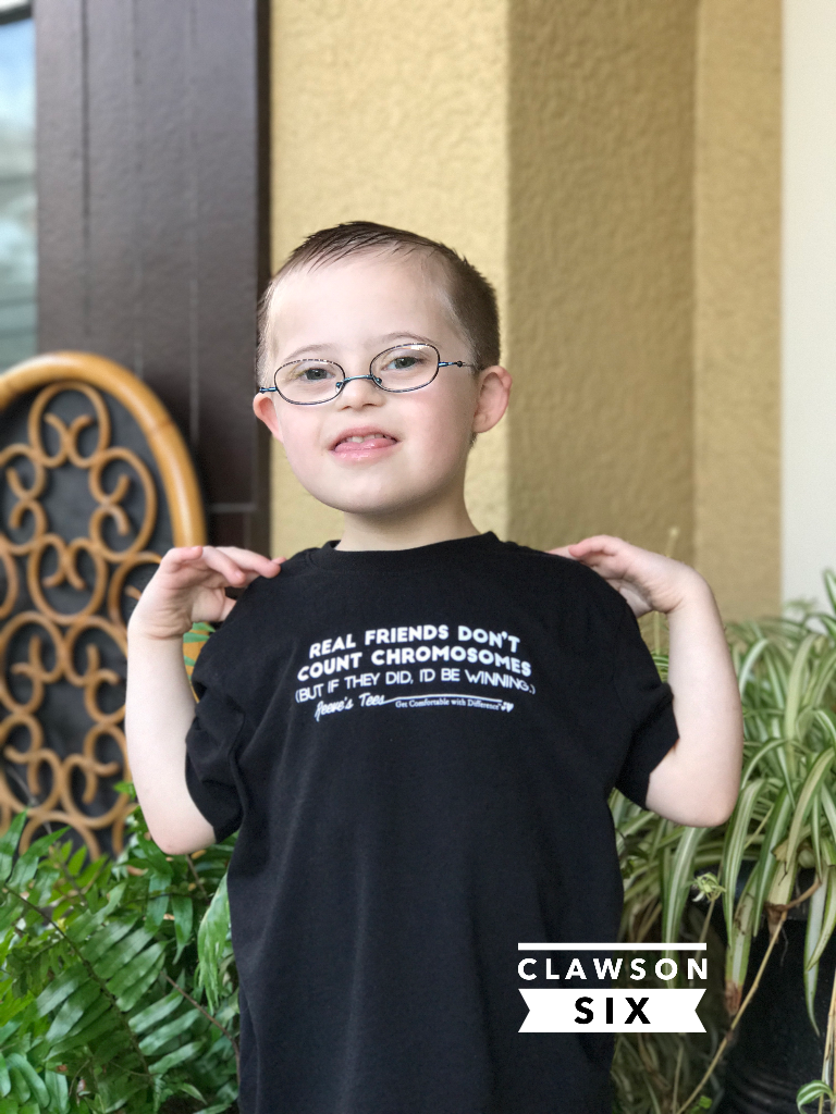 Child with Down Syndrome wearing ironic t-shirt that reads Real Friends Don't Count Chromosomes, but if they I'd be winning