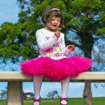 Child with Down syndrome plays with flower on picnic bench in the park