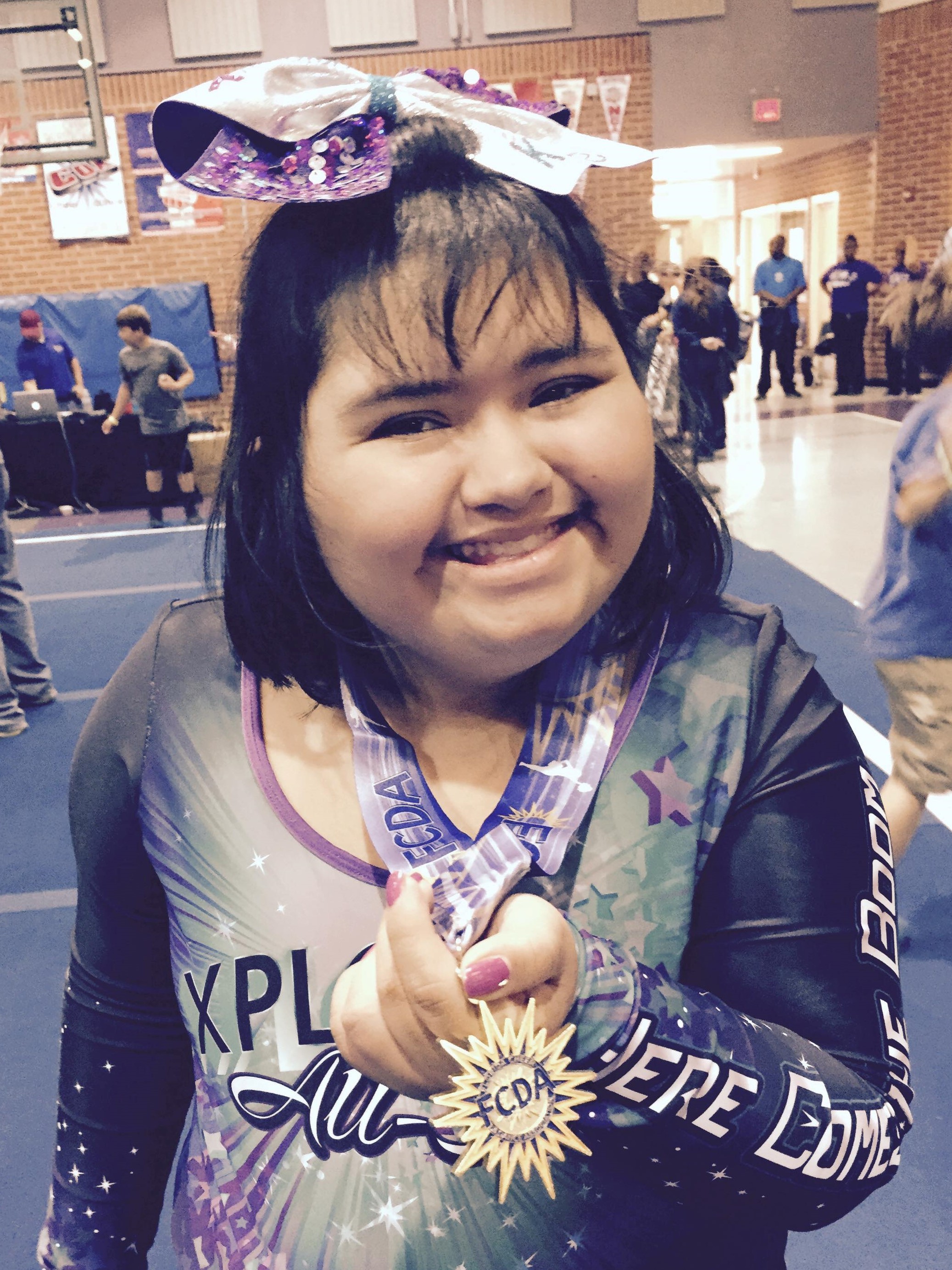 Little girl holding up her gymnastics medal and smiling